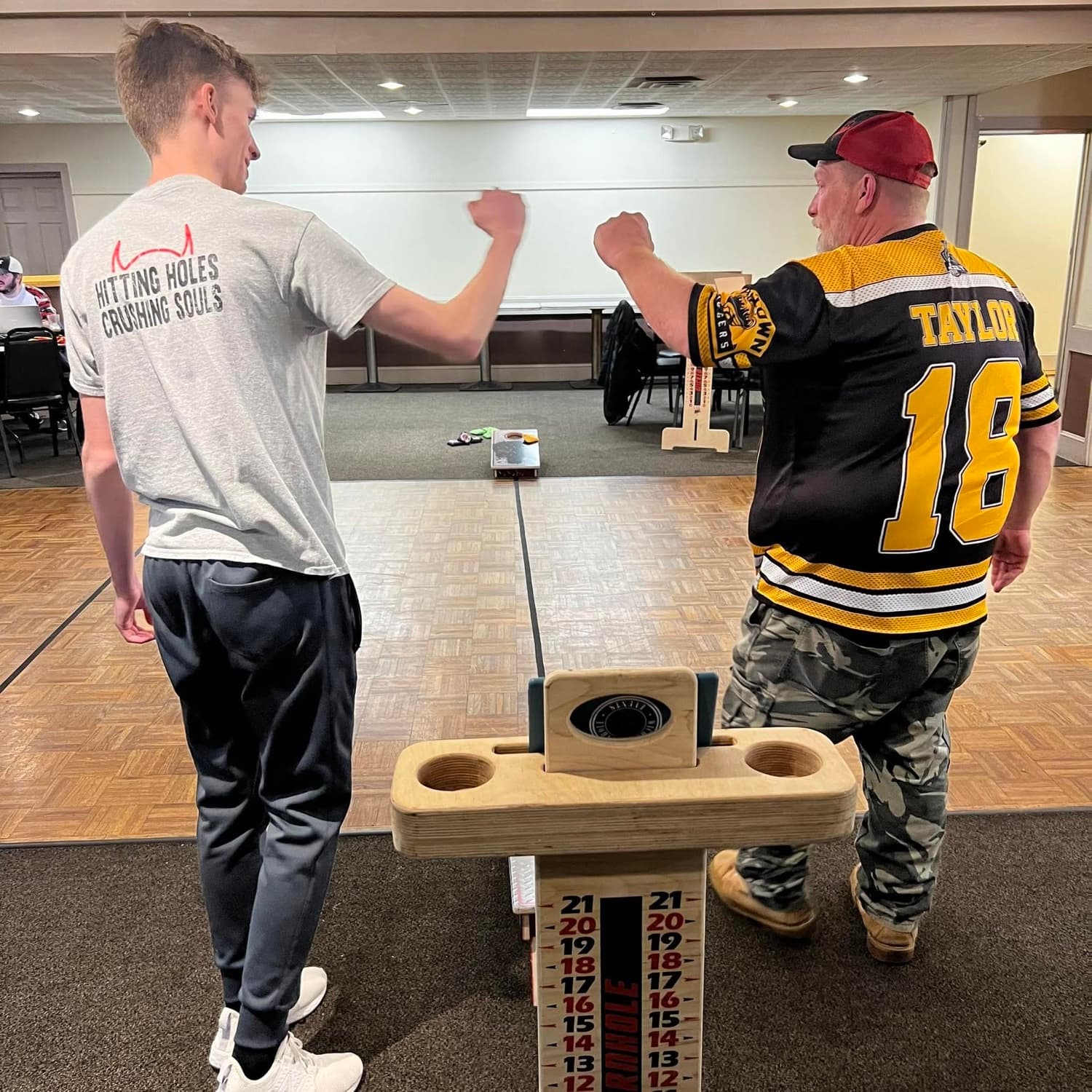 Zack and Bruce Taylor facing off across a cornhole board