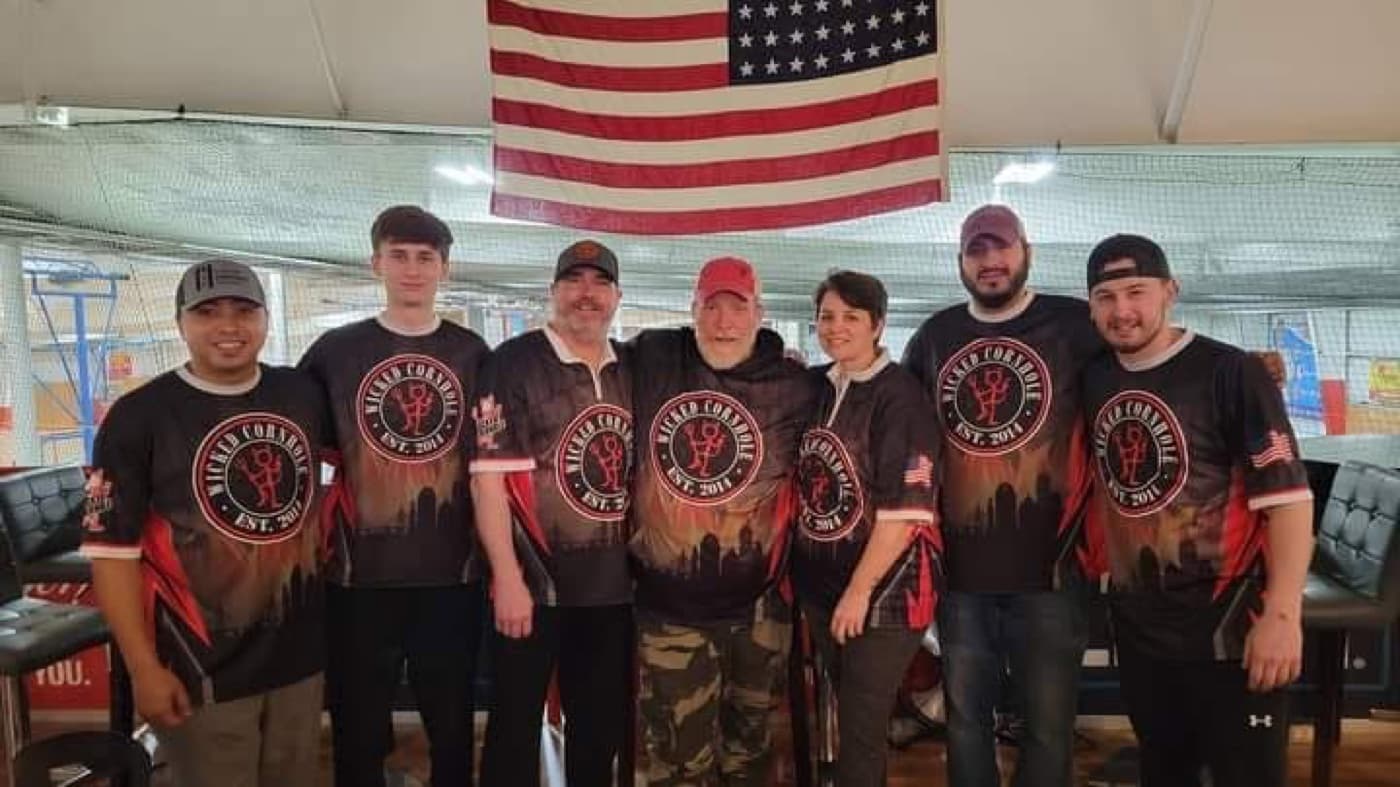 Team Wicked Cornhole in jerseys under the flag